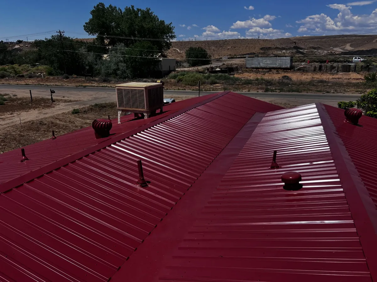 Red standing rib metal roof with turbine vents installed along the ridge