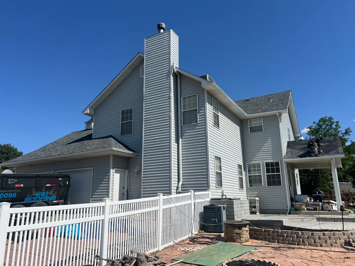 Two story home with a gray shingle roof and side chimney